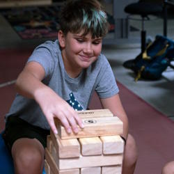 Student place Jenga blocks on top of the stack. 