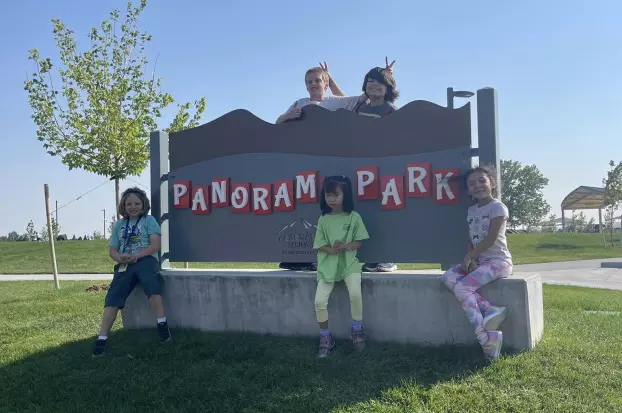 Five students sitting by Park Sign that reads Panorama Park