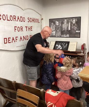 Four preschoolers with a male alumni in the history museum