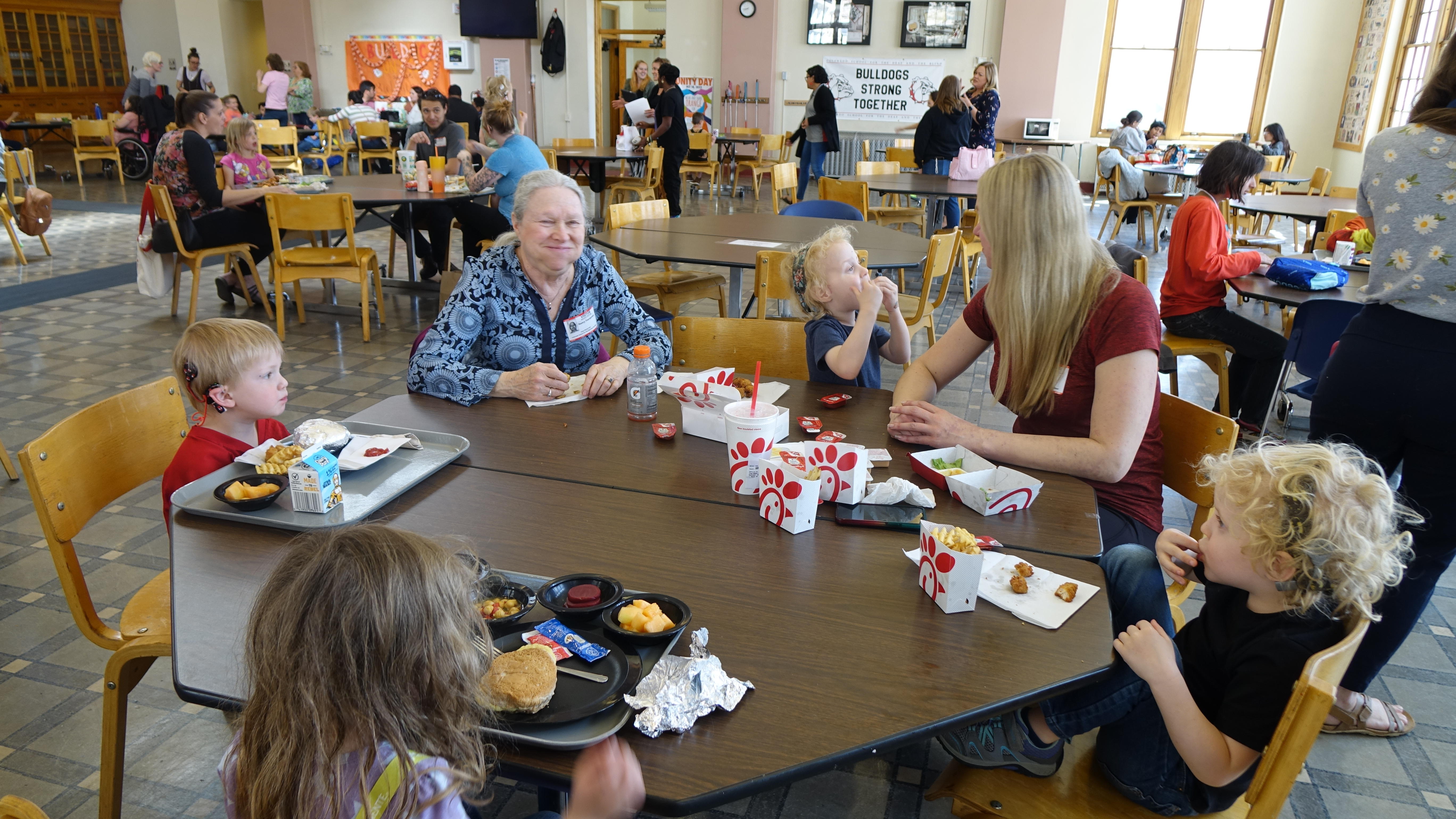Mom and grandma eat lunch with twin boys and two other children