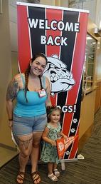  young girl and her mom pose next to the Welcome Back Bulldogs banner