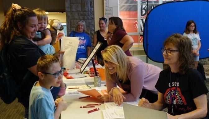 Four staff members assist a family at the registration welcome table