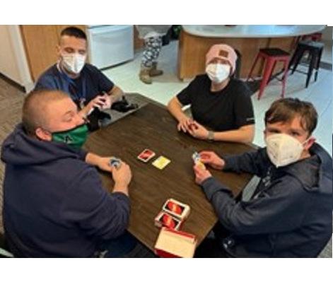 Four students play UNO, a card game that is brailled