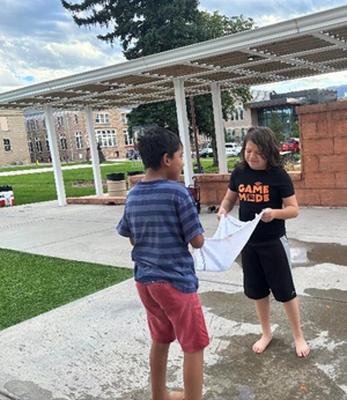 Two students holding a towel soaked in water.