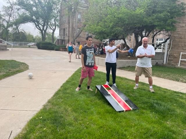 Three males play cornhole