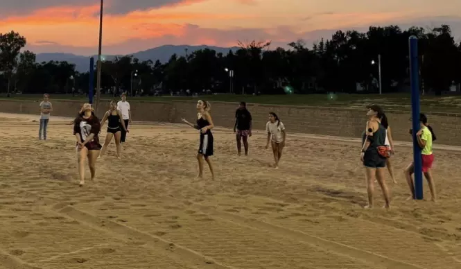 students playing volleyball on a sand court