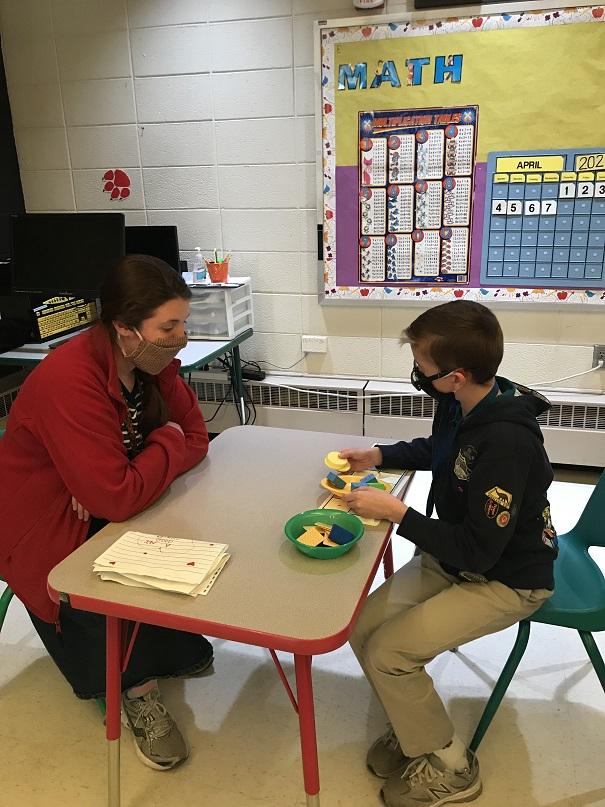 Boy holds objects during math lesson with teacher