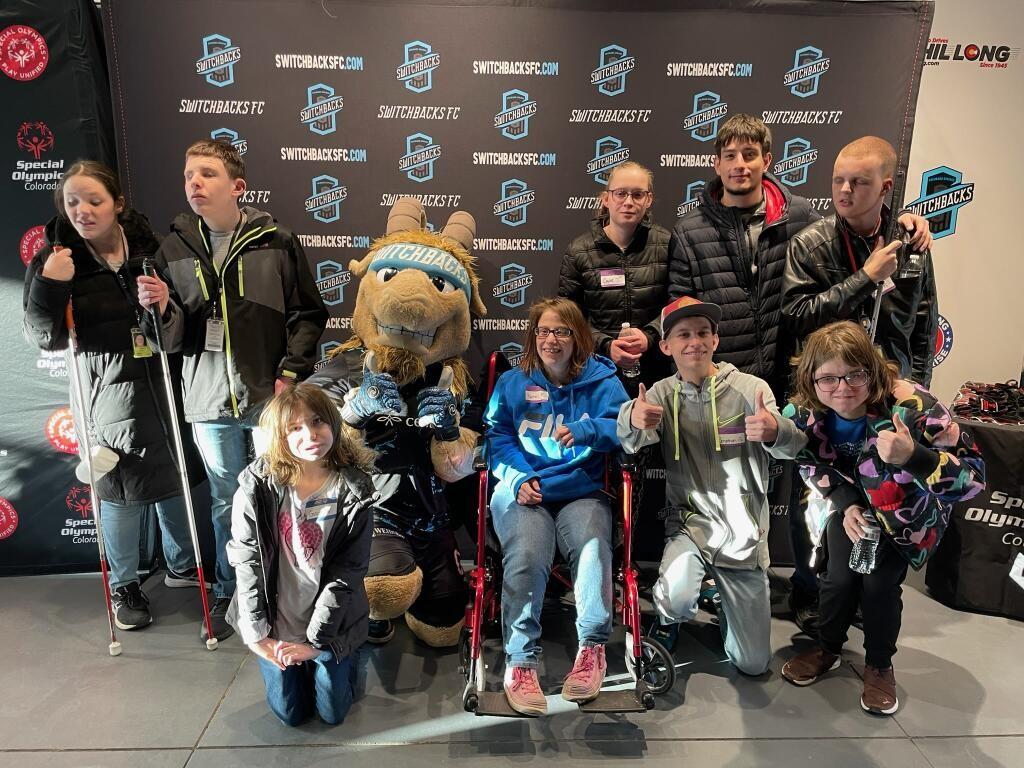 Nine students surround the Switchbacks' mascot