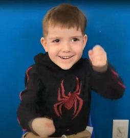 Young boy using ASL to sign "truck" while he smiles
