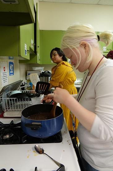 two young ladies cook at the stove