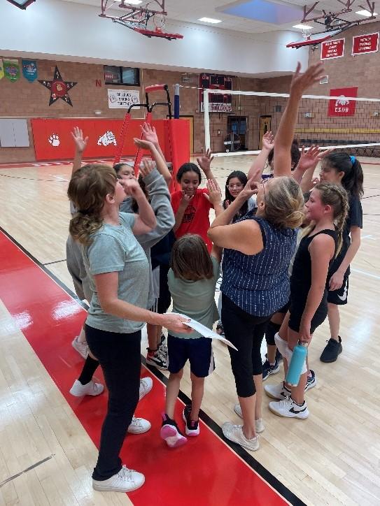 The CSDB Volleyball team standing in a circle giving each other high fives.