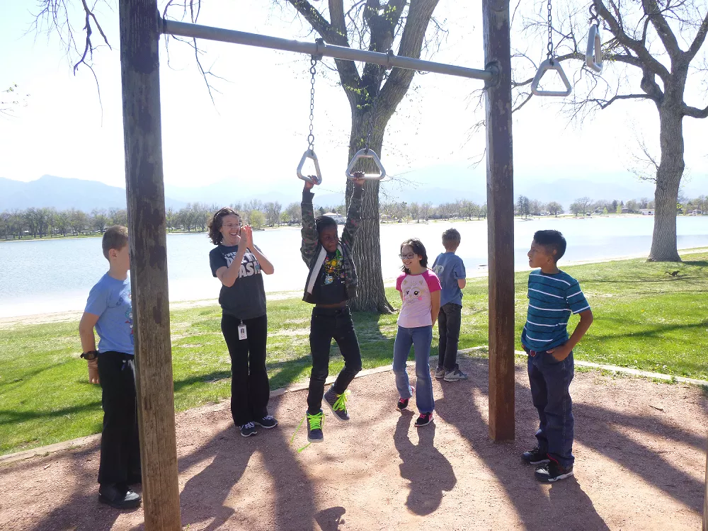 students with dorm supervisor playing on rings in the park