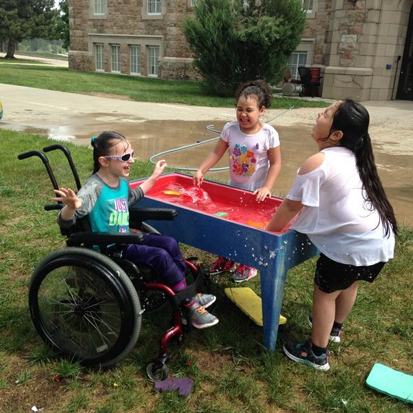 3 girls outside playing at a water table