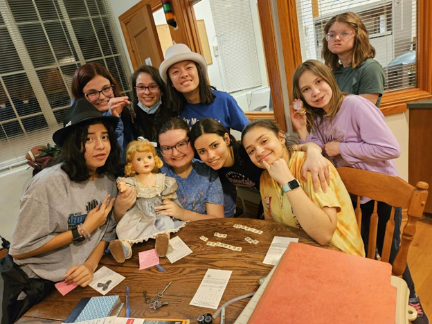 9 girls around a table with Escape Room clues