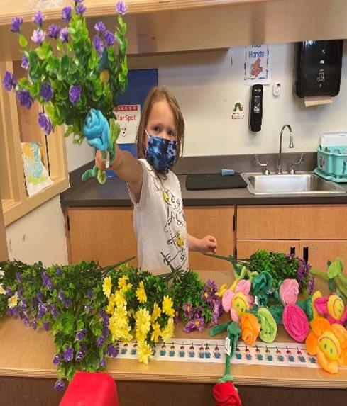 Boy holds up a bunch of flowers in a bouquet