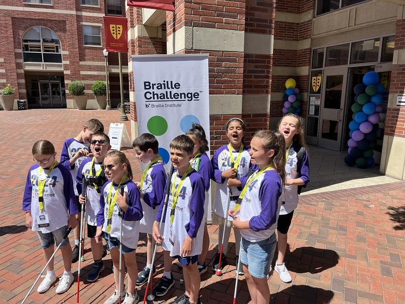 10 students who are blind, holding white canes and wearing Braille Challenge shirts