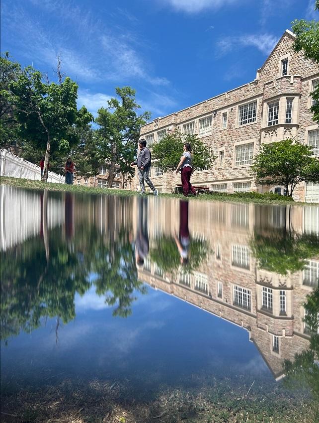 Teens walking outside and a building are reflected in an "imaginary" lake