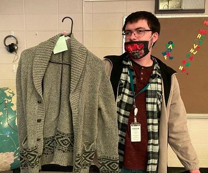 Male students holds up sweater on a hanger