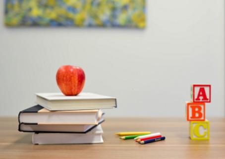 Pile of books with apple on top and toy blocks