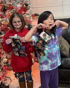 two girls hold up the stockings they sewed
