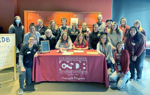Outreach Staff standing around a table with the CSDB logo.