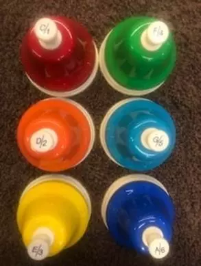 6 colorful hand bells arranged as in braille cell order