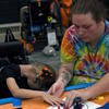 A teacher's aide helps a student feel the stickers on her pumpkin.